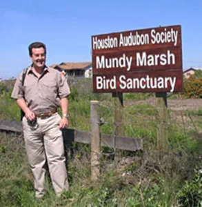 Attorney Jeff Mundy standing next to Houston Audubon Society Mundy Marsh Bird Sanctuary sign