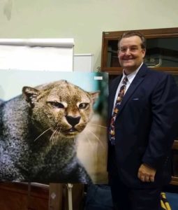 Photo of Jeff Mundy standing by animal painting